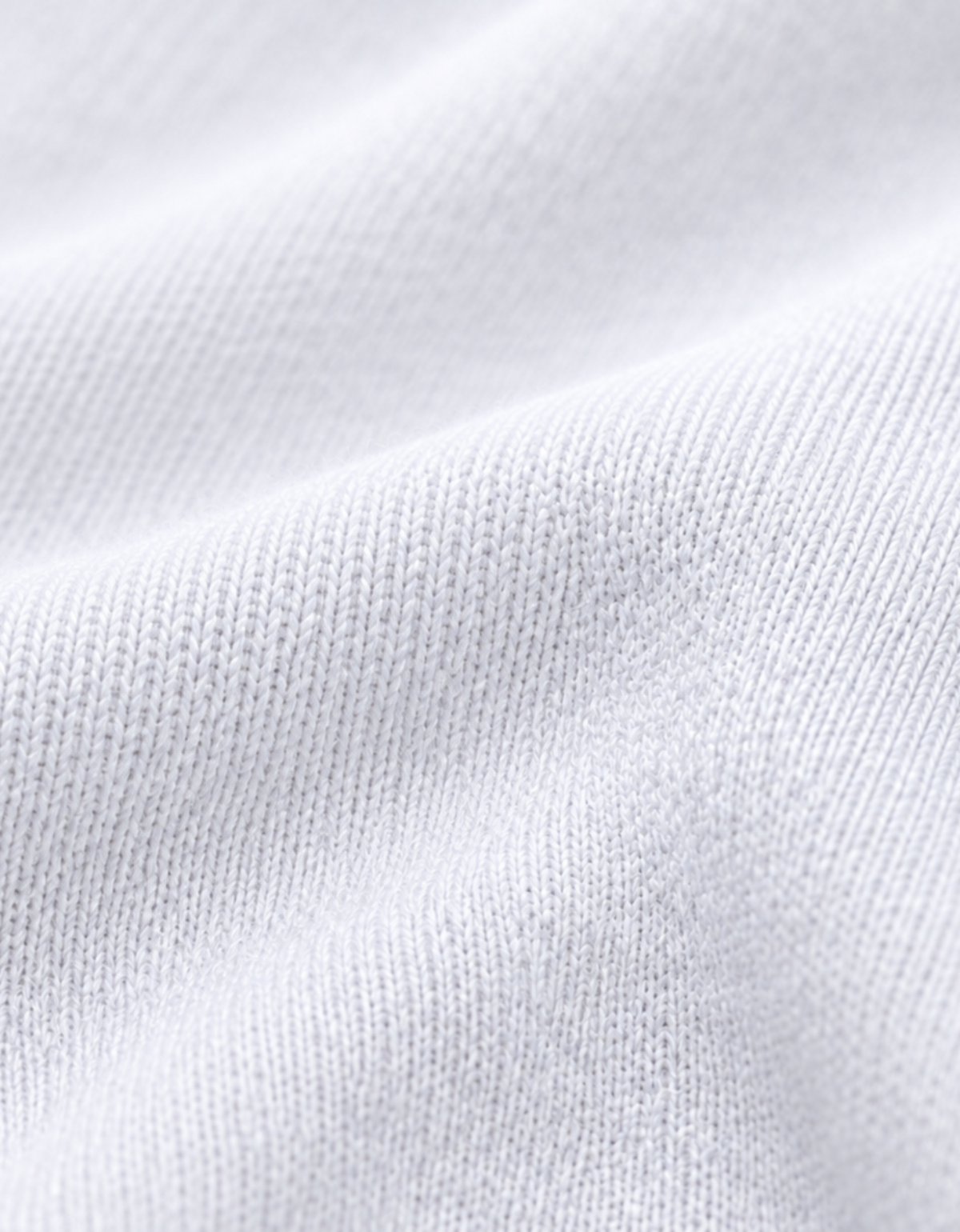 Close-up of a white ribbed knit fabric texture with soft folds and fine woven detail.