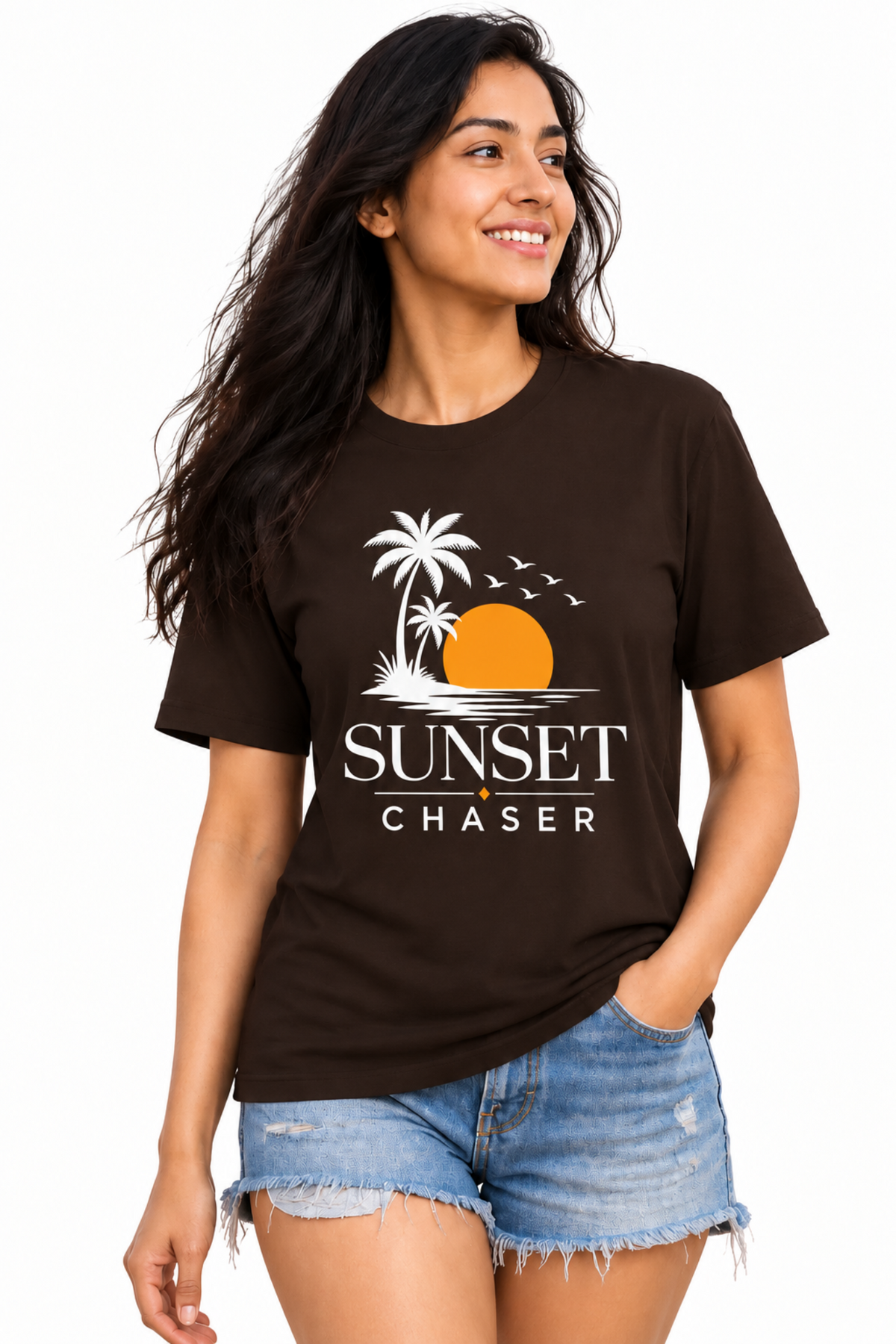 A woman modeling a dark brown t-shirt with a 'Sunset Chaser' graphic print, paired with denim shorts, against a plain white background.
