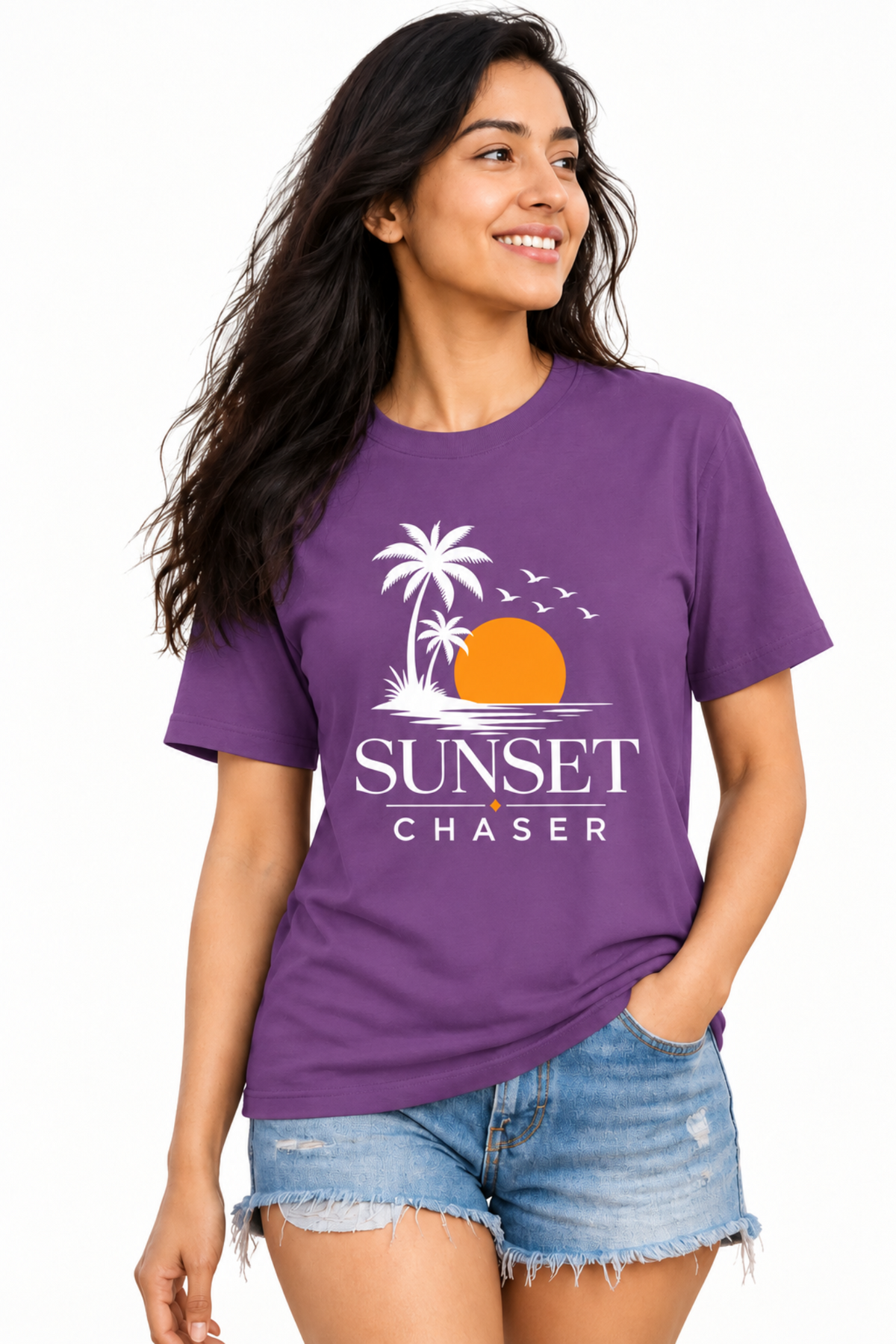 A woman modeling a purple short-sleeve graphic t-shirt with a white palm tree, orange sun, and 'SUNSET CHASER' text, paired with denim shorts against a plain white background.