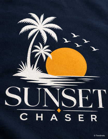 Close-up of a navy blue fabric product featuring a white and orange graphic of palm trees, a sunset, birds, and the text 'SUNSET CHASER'.
