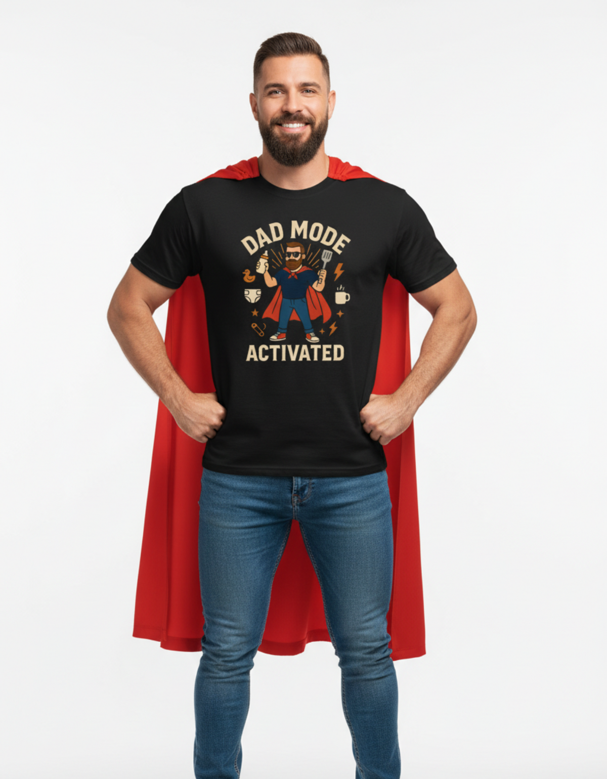 A man wearing a black graphic t-shirt with a red cape and blue jeans, posing against a light gray background. The t-shirt features a graphic of a superhero with the text 'DAD MODE ACTIVATED'.