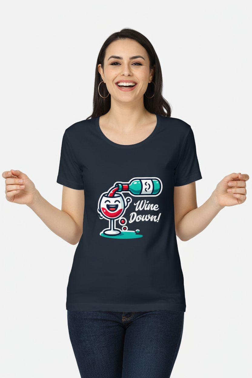 A woman smiling and wearing a dark navy blue t-shirt with a cartoon graphic of a wine glass, a bottle, and the text 'Wine Down!' in white, paired with dark blue jeans, against a light gray background.
