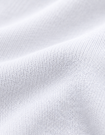 Close-up of a white ribbed knit fabric texture with soft folds and fine woven detail.