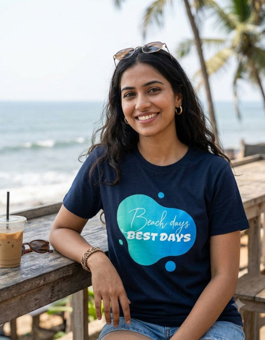 Woman wearing Trendmelo Beach Days Best Days navy blue lightweight 160 GSM Supima cotton graphic tee at a coastal seaside cafe