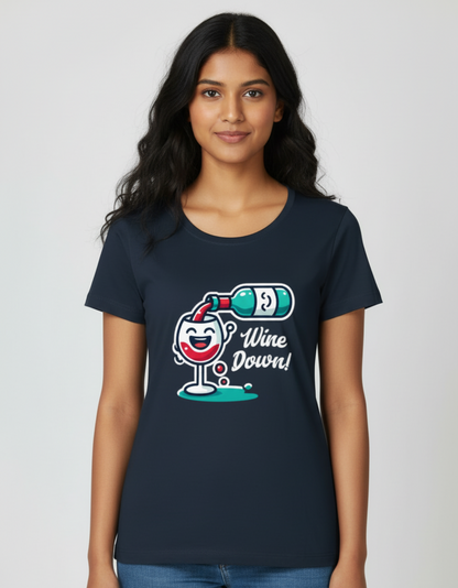 A woman wearing the navy blue Wine Down graphic tee holding a glass of wine on a couch, illustrating a soft bio-washed cotton t-shirt for weekend lounging.