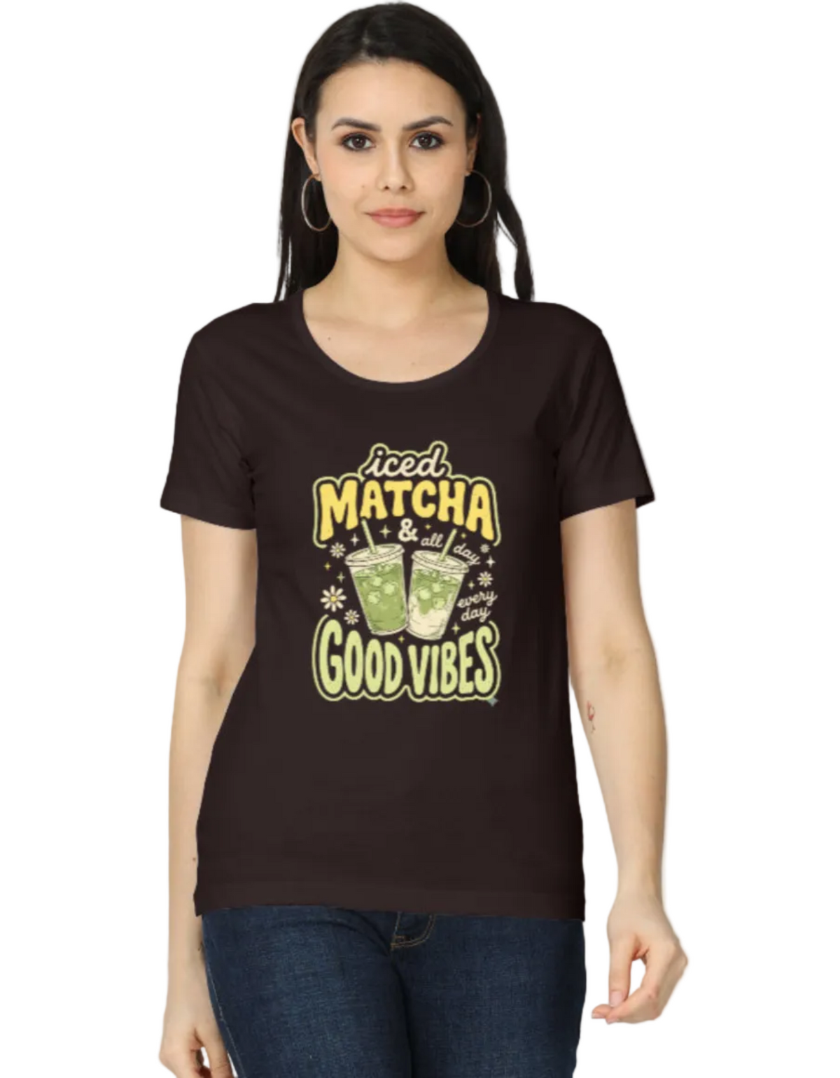 A woman modeling a dark brown short-sleeve t-shirt with a 'Good Matcha & Tea Time Good Vibes' graphic print on the front, paired with blue jeans against a plain white background.